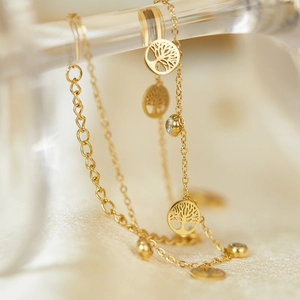 Close-up of golden Tree of Life charms with micro-pave zircons on a delicate chain
