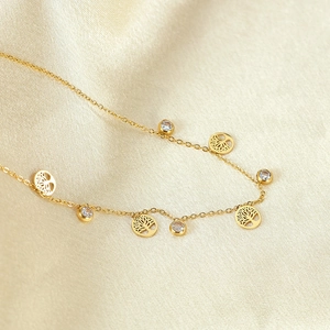 Close-up of gold stainless steel anklet with Tree of Life charms and zircon pendants