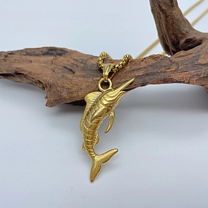 Detailed close-up of golden marlin fish pendant with box chain on a wooden branch