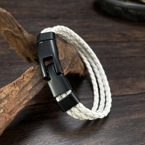 Detail of white braided leather bracelet with black matte metal buckle on wood