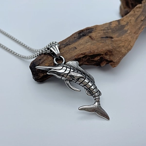 Macro detail of marlin fish pendant in antique silver finish on natural wood stand