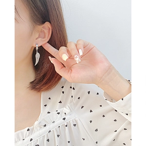 Detail of silver stainless steel wing earring worn on ear showing texture and size