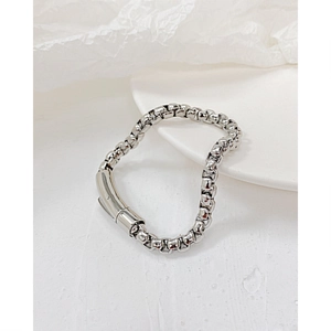 Detailansicht eines schweren Edelstahl-Boxarmbandes in Silber auf minimalistischem Hintergrund