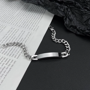 Detail of a polished stainless steel Cuban link bracelet with a blank ID nameplate tag