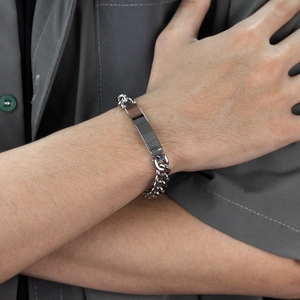 Close-up of a men's polished stainless steel Cuban link bracelet on a wrist