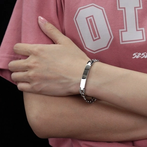 Detailed view of a sleek stainless steel Cuban link bracelet on a model wrist