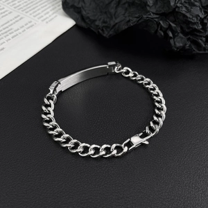 Detail of silver stainless steel Cuban chain bracelet with a brushed metal plate and clasp
