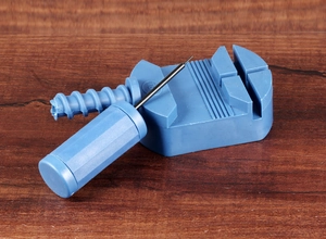 Manual blue plastic watch strap link remover tool set on a brown wooden surface