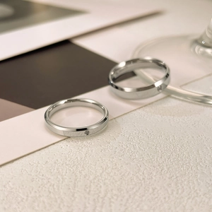 Close-up of silver stainless steel couple rings with single diamond and faceted edges
