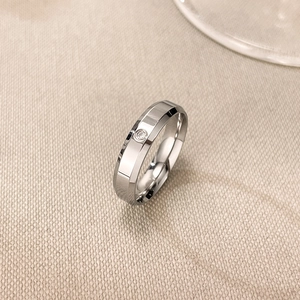 Close-up of silver stainless steel ring with faceted texture and central sparkling diamond