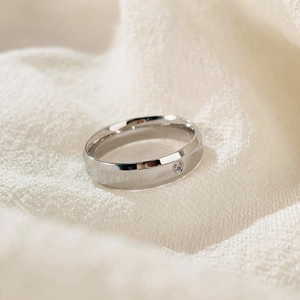 Polished titanium steel couple ring with round diamond inlay on white fabric