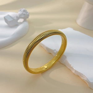 Macro shot of gold-plated tubogas bracelet with textured spiral metallic detail