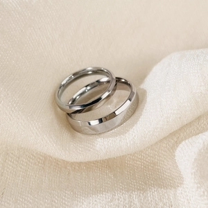 Polished silver stainless steel couple rings set with micro-inlaid diamonds on fabric
