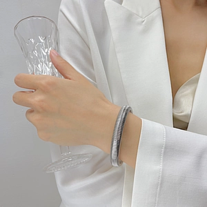 Detail of chunky stainless steel textured cuff bracelet worn by a model in a white suit