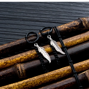 Detalle de pendientes negros de acero inoxidable con colgante de pluma y cadena larga