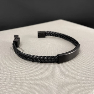 Detalle de pulsera para hombre de cuero trenzado negro con placa de metal mate y cierre magnético