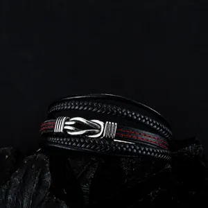 Close-up of multilayer black leather woven bracelet with red stitching and metal knot clasp