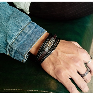 Detail of layered black leather bracelet with vintage silver knot clasp on male wrist