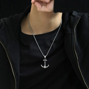 Close-up of a silver stainless steel anchor pendant necklace on a black shirt
