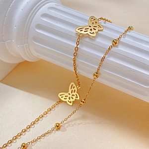 Detailaufnahme der goldenen zweilagigen Fußkette mit Schmetterling und kleinen Perlen