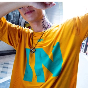 Detail of trendy 3D cube pendant necklace paired with casual graphic orange cotton t-shirt