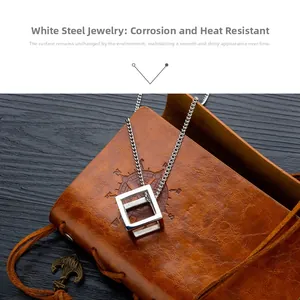 Macro detail of silver stainless steel cube pendant resting on vintage leather and wood