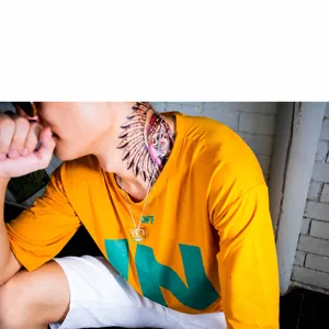 Primer plano de collar con colgante de cubo plateado en hombre con camiseta amarilla