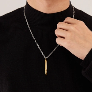 Détail du collier pendentif balle hip hop doré sur un pull noir pour homme