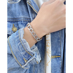 Poliertes silbernes Panzerarmband aus Edelstahl auf einem Denim-Hintergrund für Herren