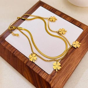 Detail einer zweilagigen Goldfußkette mit Schlangenkette und fünf Kleeblatt-Anhängern