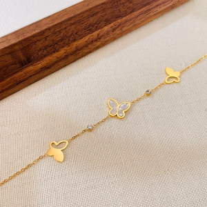 Dettaglio bracciale dorato con farfalle in madreperla bianca e piccoli zirconi