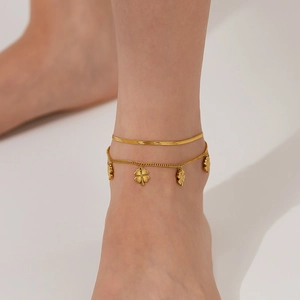 Detail einer zweischichtigen Gold-Fußkette mit Kleeblatt-Anhängern und Schlangenkette