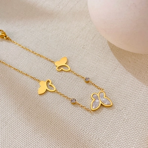 Dettaglio del bracciale farfalla dorato con madreperla bianca e accenti di zircone