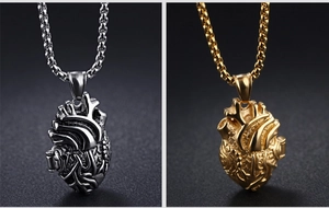 Dettaglio di ciondoli a cuore anatomico in argento e oro con catene box in acciaio