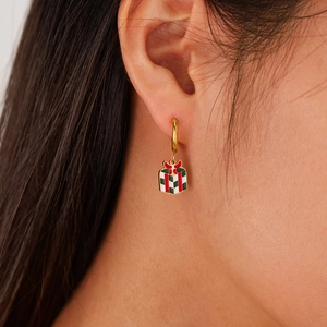 Gros plan de boucles d'oreilles pendantes boîte cadeau de Noël sur une femme