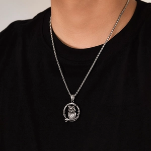 Detailopname van een vintage uil-hanger aan een vierkante gevlochten ketting