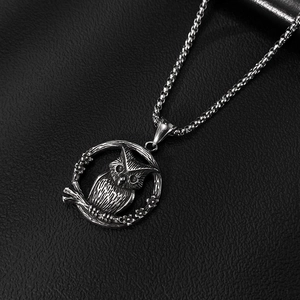 Detailopname van de uil-reliëfhanger en duurzame parelketting in een vintage zilveren kleur