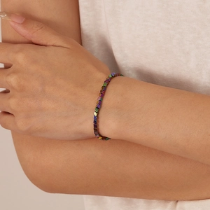 Detailopname van een iriserende zeshoekige kralenarmband om de pols van een model