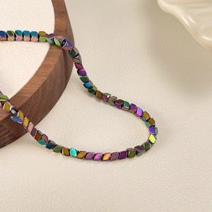 Detailopname van iriserende regenboog metalen kubuskraaltjes aan een fijne ketting