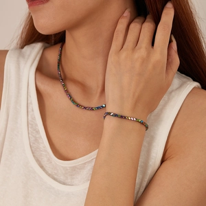 Detail van roestvrijstalen ketting en armband set met regenboog iriserende kralen