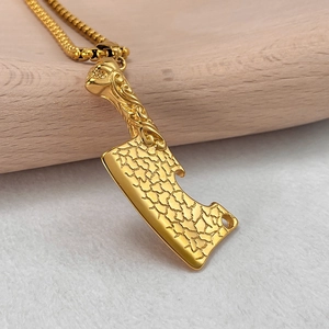 Détail macro du pendentif couperet doré avec textures de crâne et gravures rock