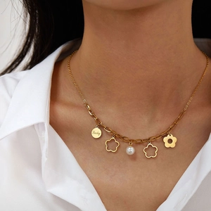 Collana dorata con ciondolo Lucky, fiori traforati e perla indossata da modella