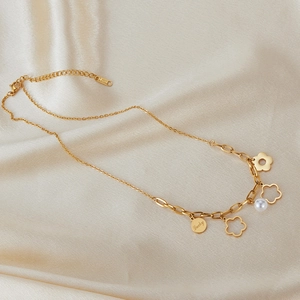 Dettaglio della collana in acciaio dorato con fiori traforati, ciondolo Lucky e perla