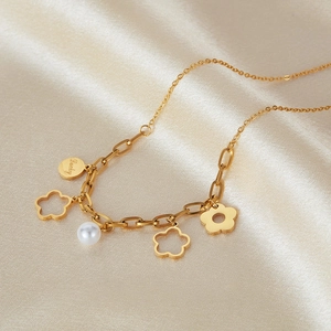 Dettaglio della collana floreale dorata con ciondoli traforati, perla e tag Lucky