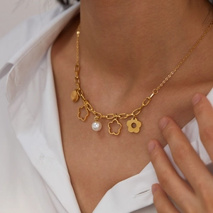 Dettaglio della collana con ciondoli a fiori dorati e perla bianca su catena a maglie