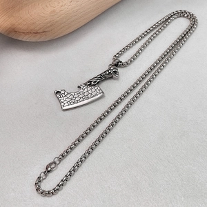 Vue macro détaillée du pendentif hache rétro avec textures sur une chaîne en acier inoxydable