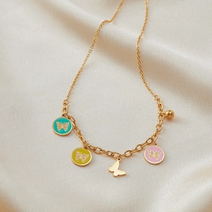 Detailansicht eines goldenen Edelstahl-Armbands mit bunten Emaille-Schmetterlingen auf Seide