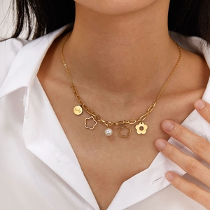 Dettaglio della collana a fiori dorati con perla bianca e ciondolo Lucky su camicia