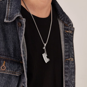 Détail du pendentif couperet punk vintage avec texture fissurée sur chaîne en acier