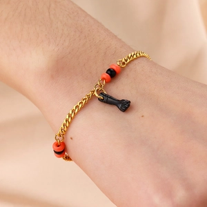 Bracelet en acier doré avec perles rouges noires et pendentif poing Figa sur le poignet